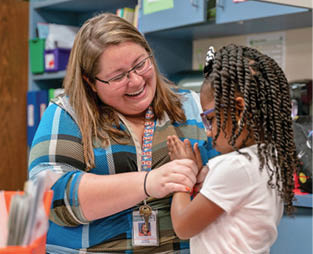 Teacher playing patty-cake with student, Spring ISD