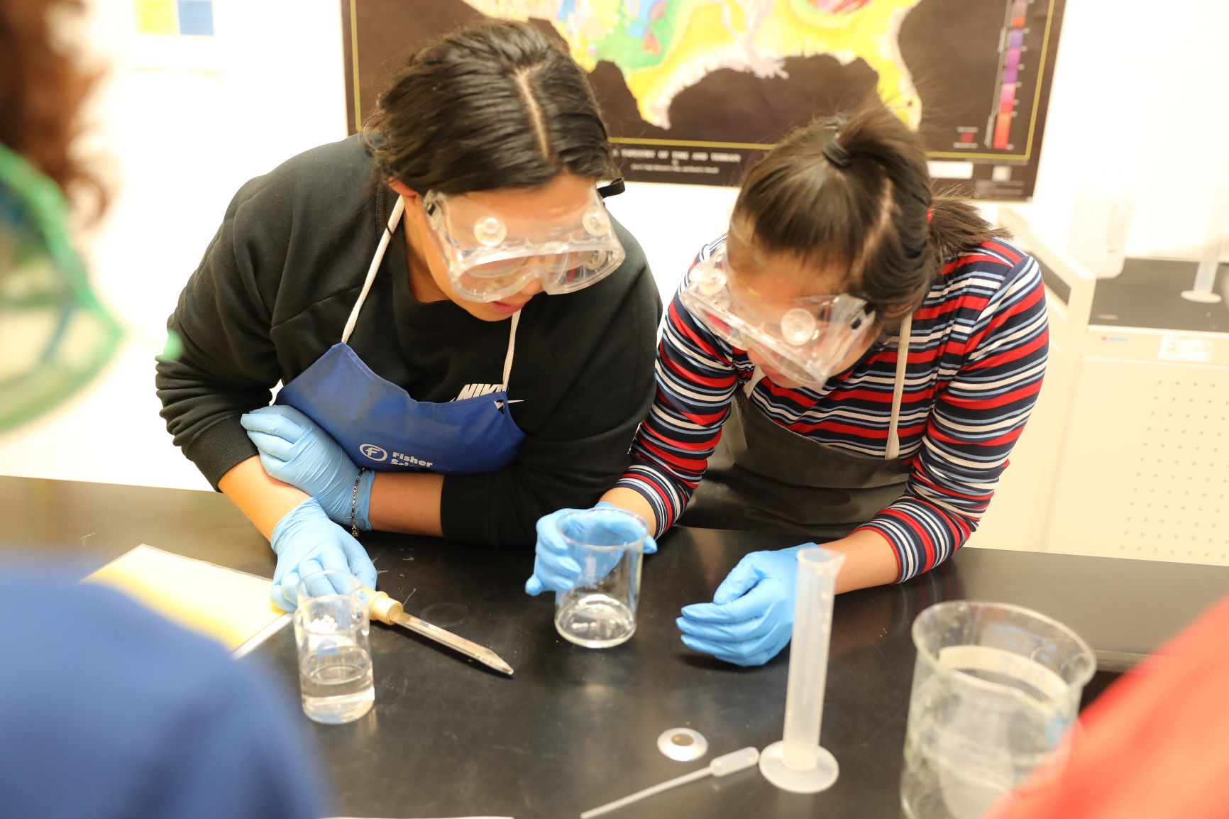 Photo of two girls viewing a beaker in science class. 