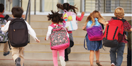 Photo of children with bookbags running up the stairs.