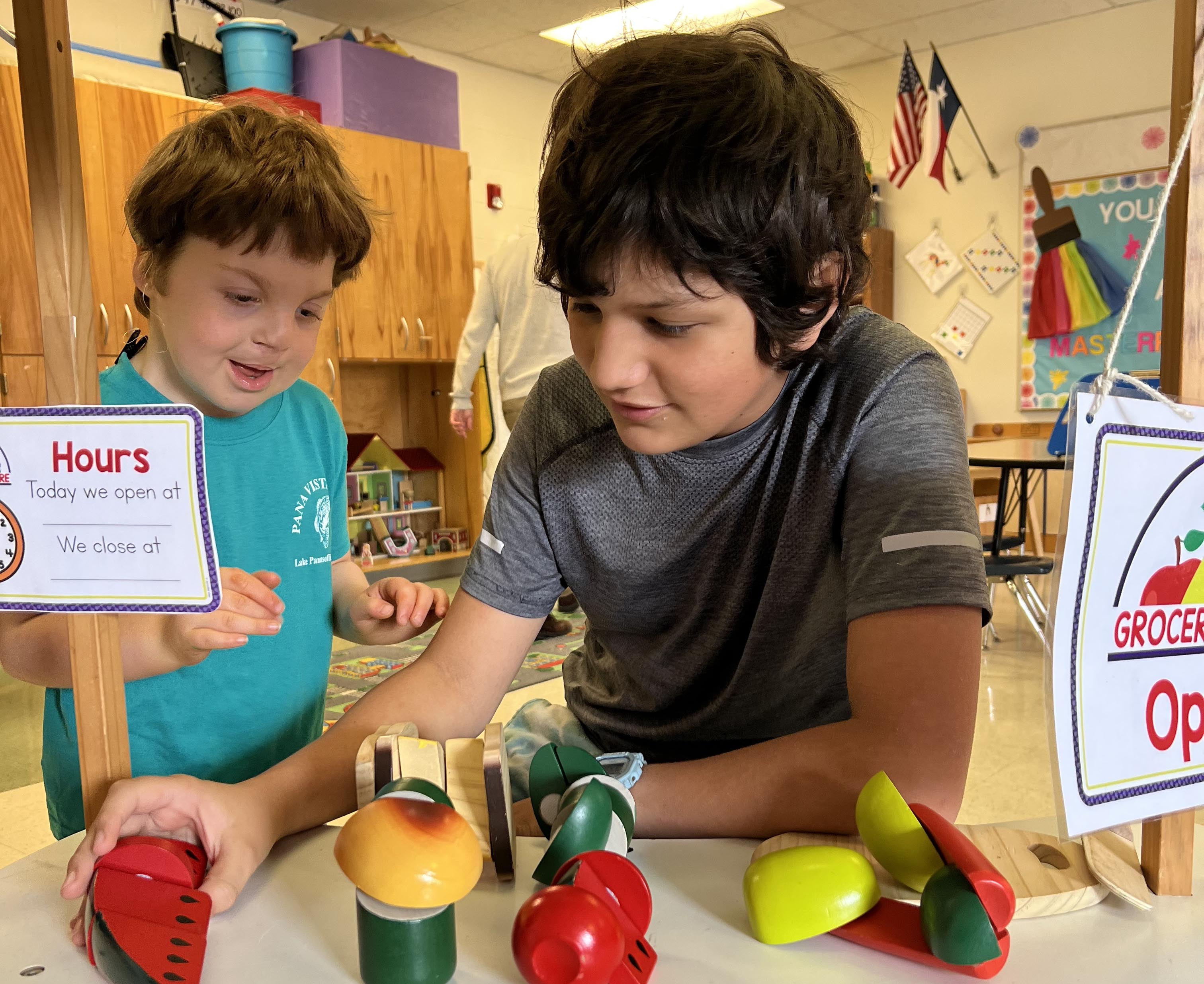 Two boys operating a pretend grocery store in a life skills classroom. 